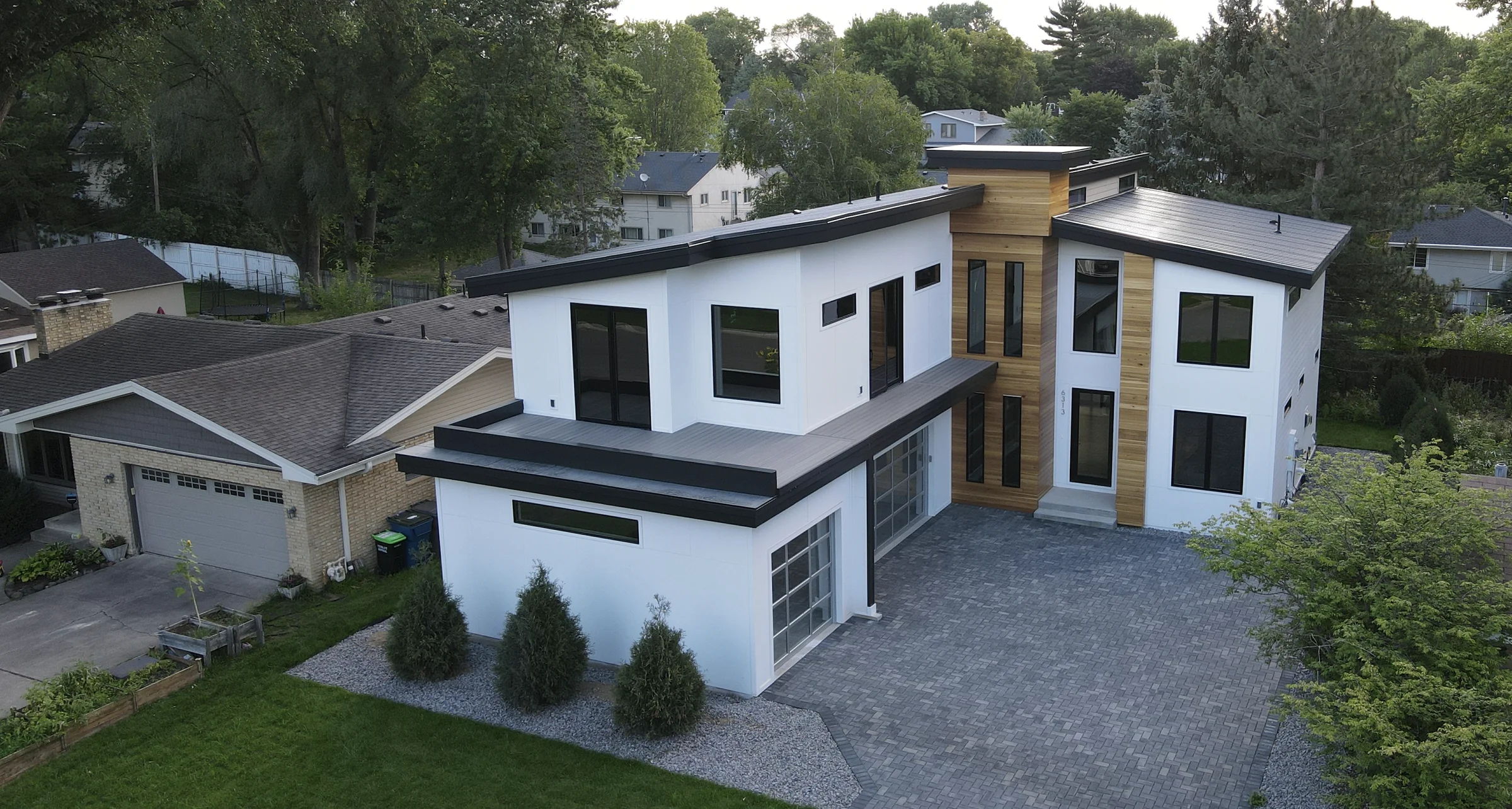 Modern white home with wood accents and a dark metal roof